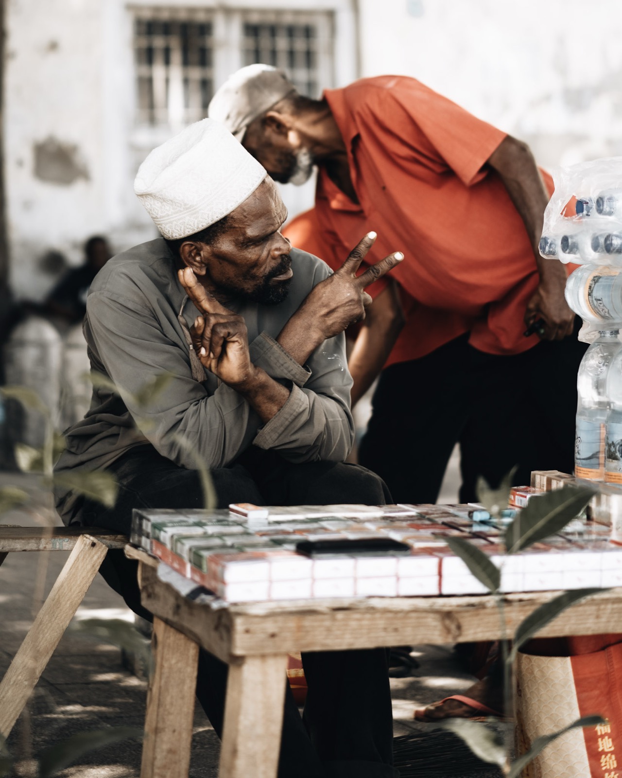 Two men interacting at a market stall in a Zanzibar east coast fishing village