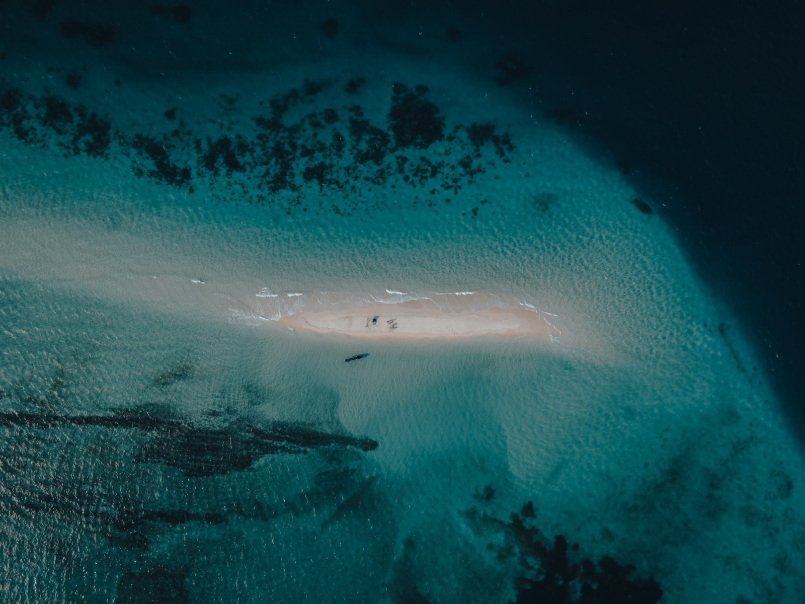 Aerial view of a narrow sandbar island surrounded by turquoise Indian Ocean water and coral reefs — Mnemba Atoll, north-east Zanzibar