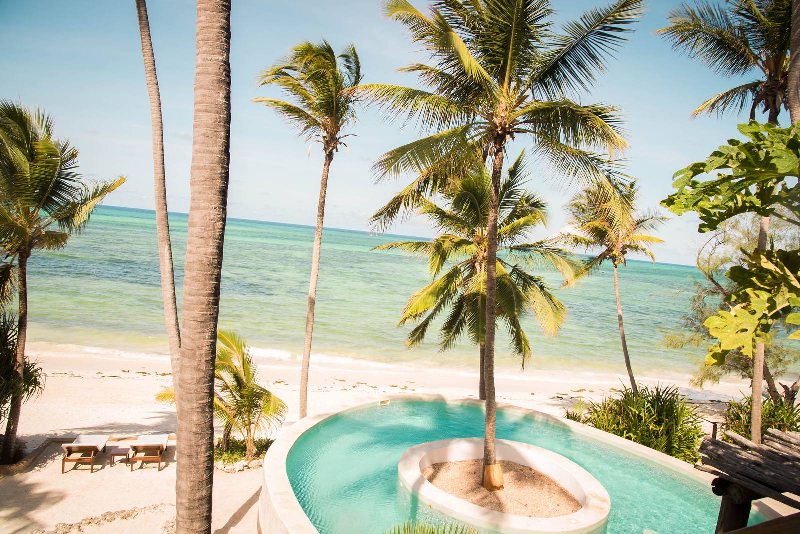 Palms and a round plunge pool above a white beach and turquoise sea, Zanzibar